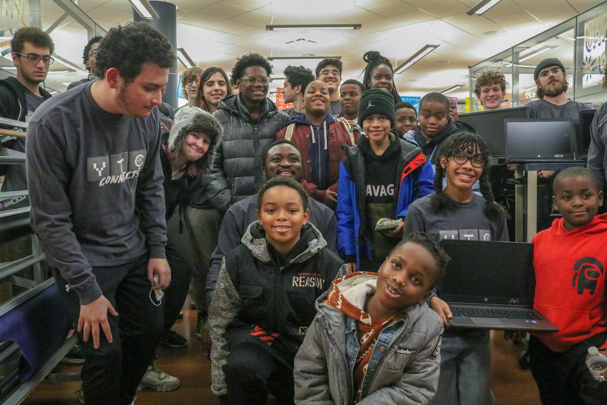 Students handing refurbished computers to Camp Kuumba families